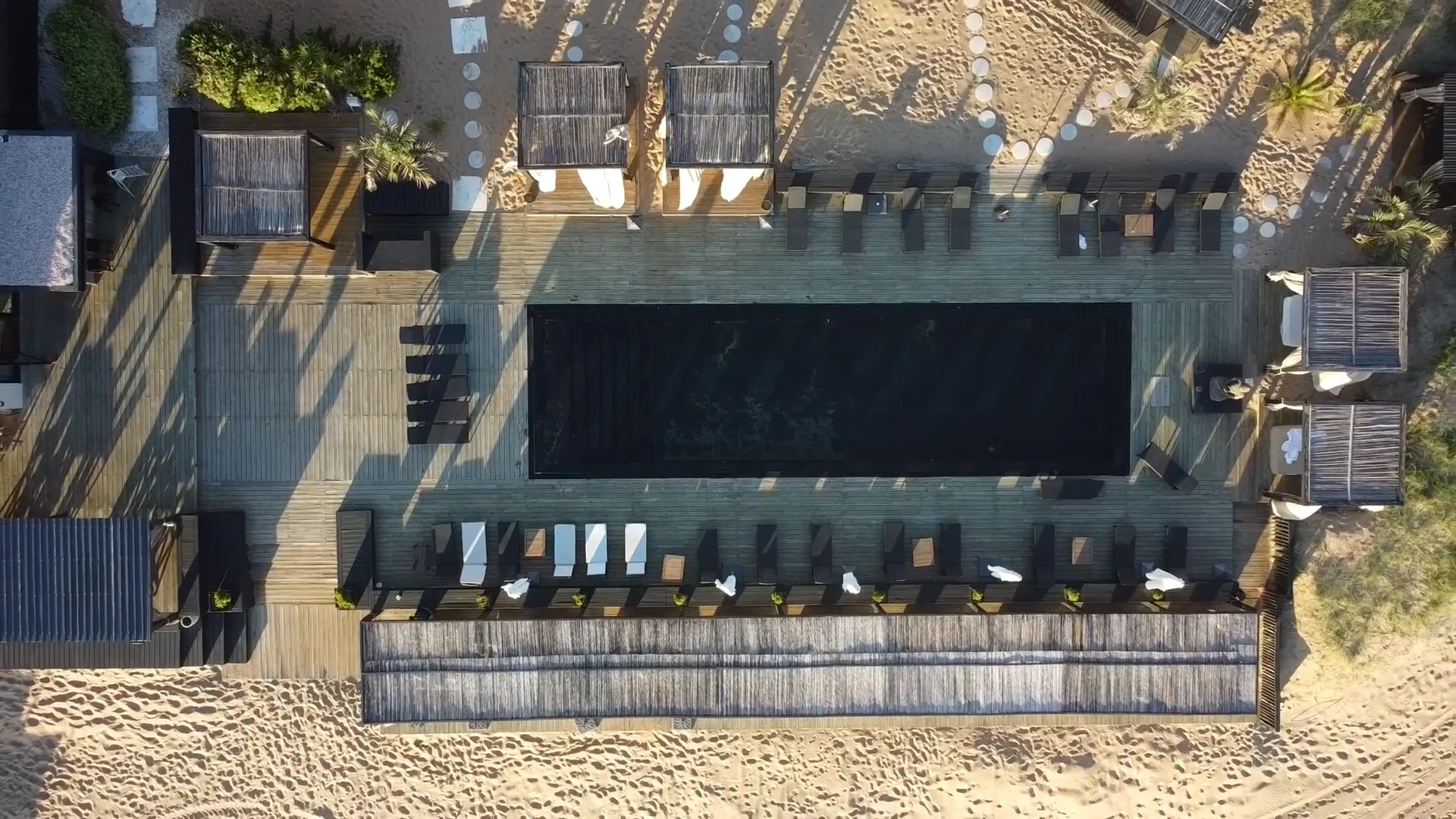 Aerial view of a hotel pool area with lounge chairs and cabanas.